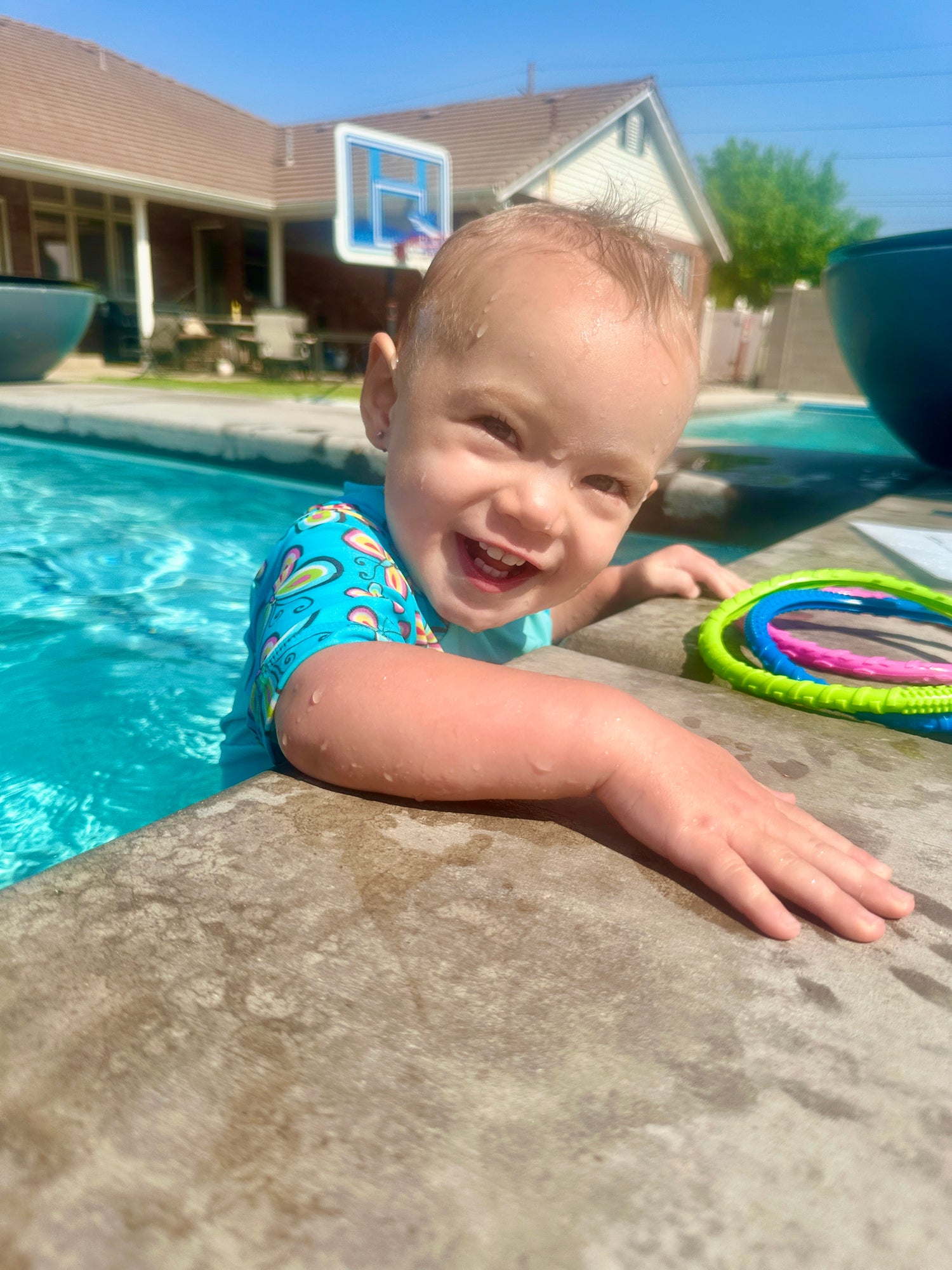 toddler wet and smiling in the pool 